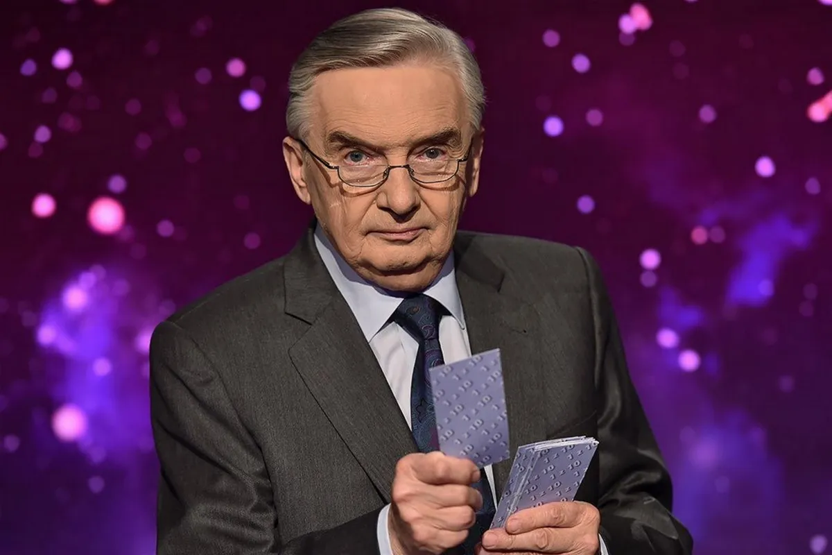 Starszy mężczyzna w garniturze trzyma karty z napisem 