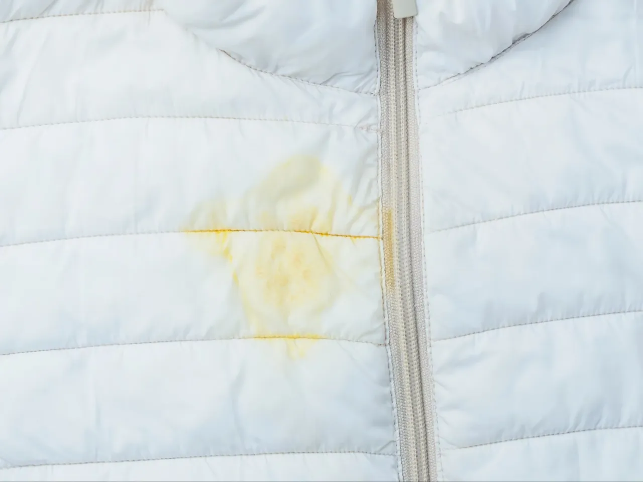 Ż&oacute;łta plama na białej kurtce puchowej. Dowiedz się, jak usunąć plamę z kurtki puchowej, aby zn&oacute;w wyglądała jak nowa.