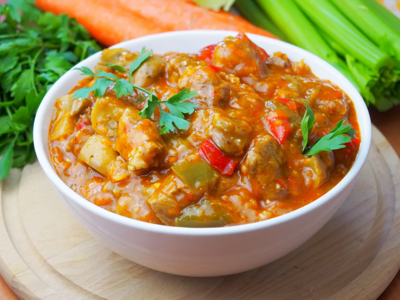 Pyszne gulasz z łopatki na obiad, z papryką i warzywami, udekorowany natką pietruszki.