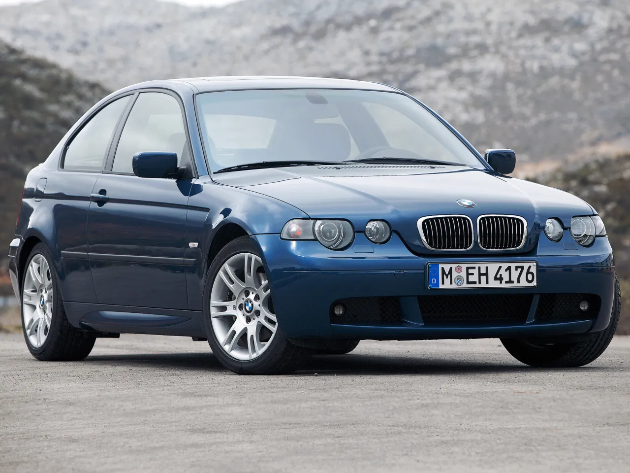 Niebieskie BMW Serii 3 Compact (E46) z lat produkcji 2001-2004 na tle górskiego krajobrazu.