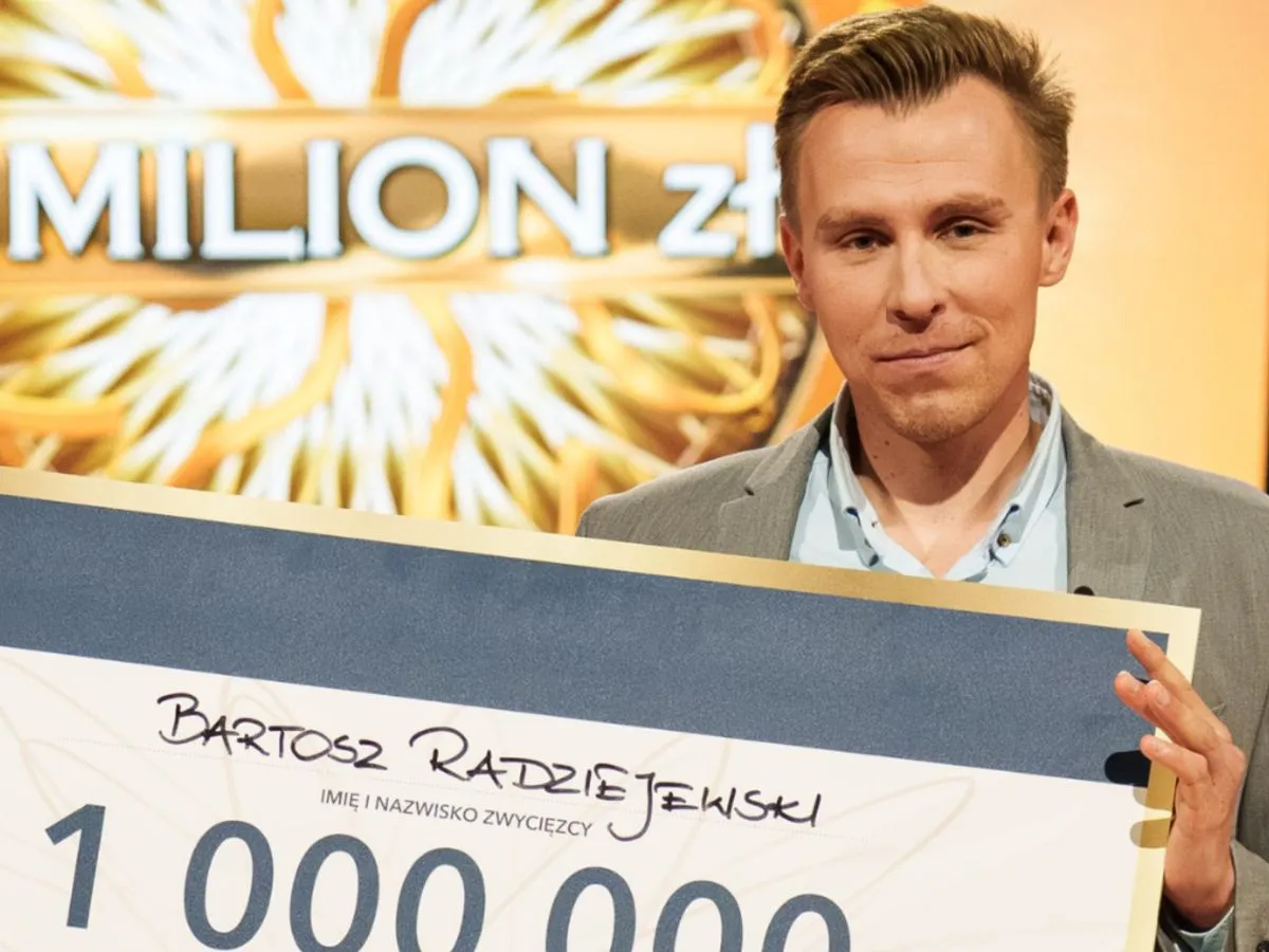 Bartosz Radziejewski, jeden z milionerów, kto wygrał milion złotych, trzyma czek.