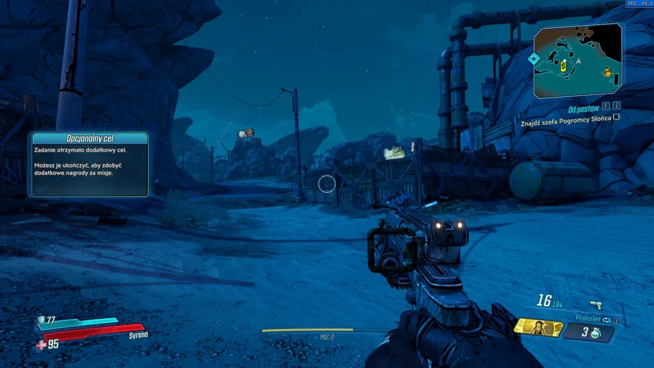 Gra Borderlands 3 spolszczenie. Widok z perspektywy pierwszej osoby na pustynny krajobraz z budynkami i bronią w ręku.