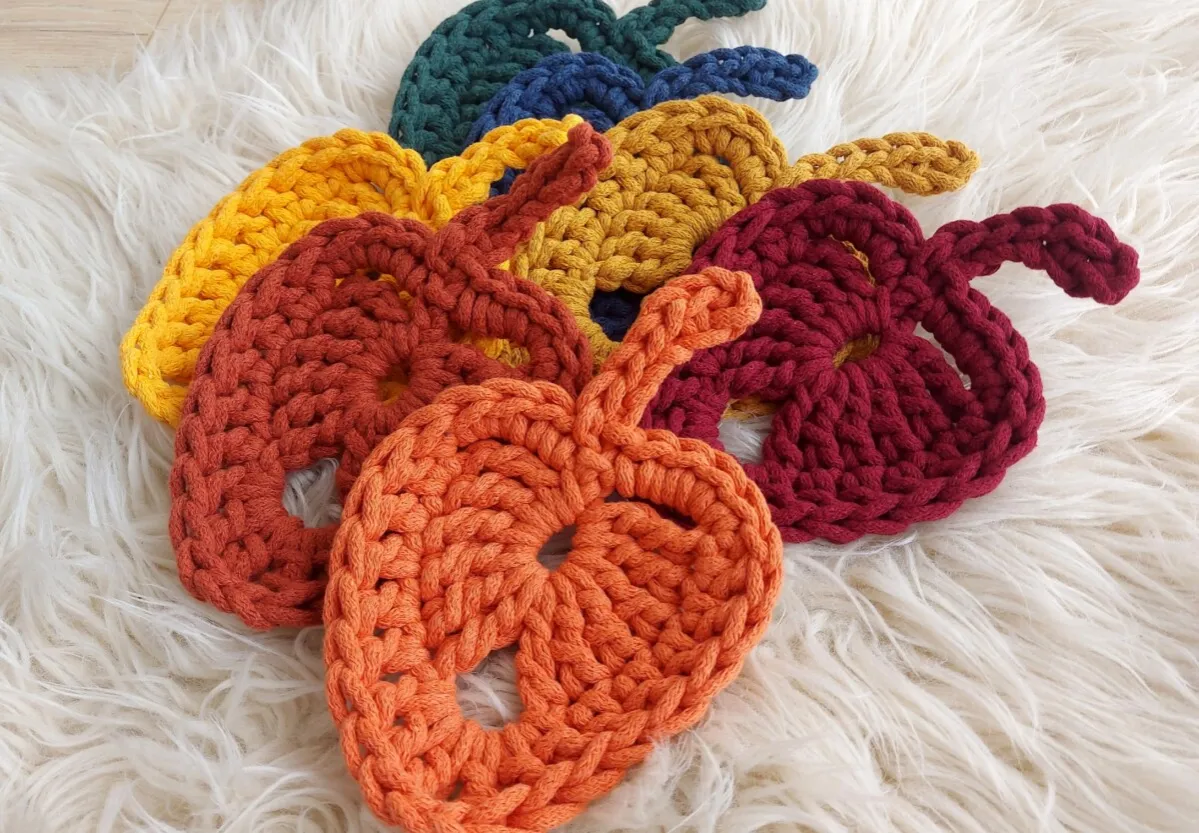 Kolorowe, szydełkowe podkładki pod kubek w kształcie dyni, wykonane z grubego sznurka. Idealne na jesienny stół.