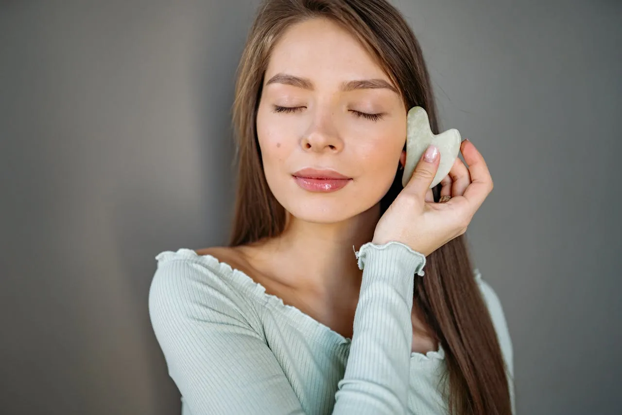 kobieta wykonująca masaż gua sha na twarzy