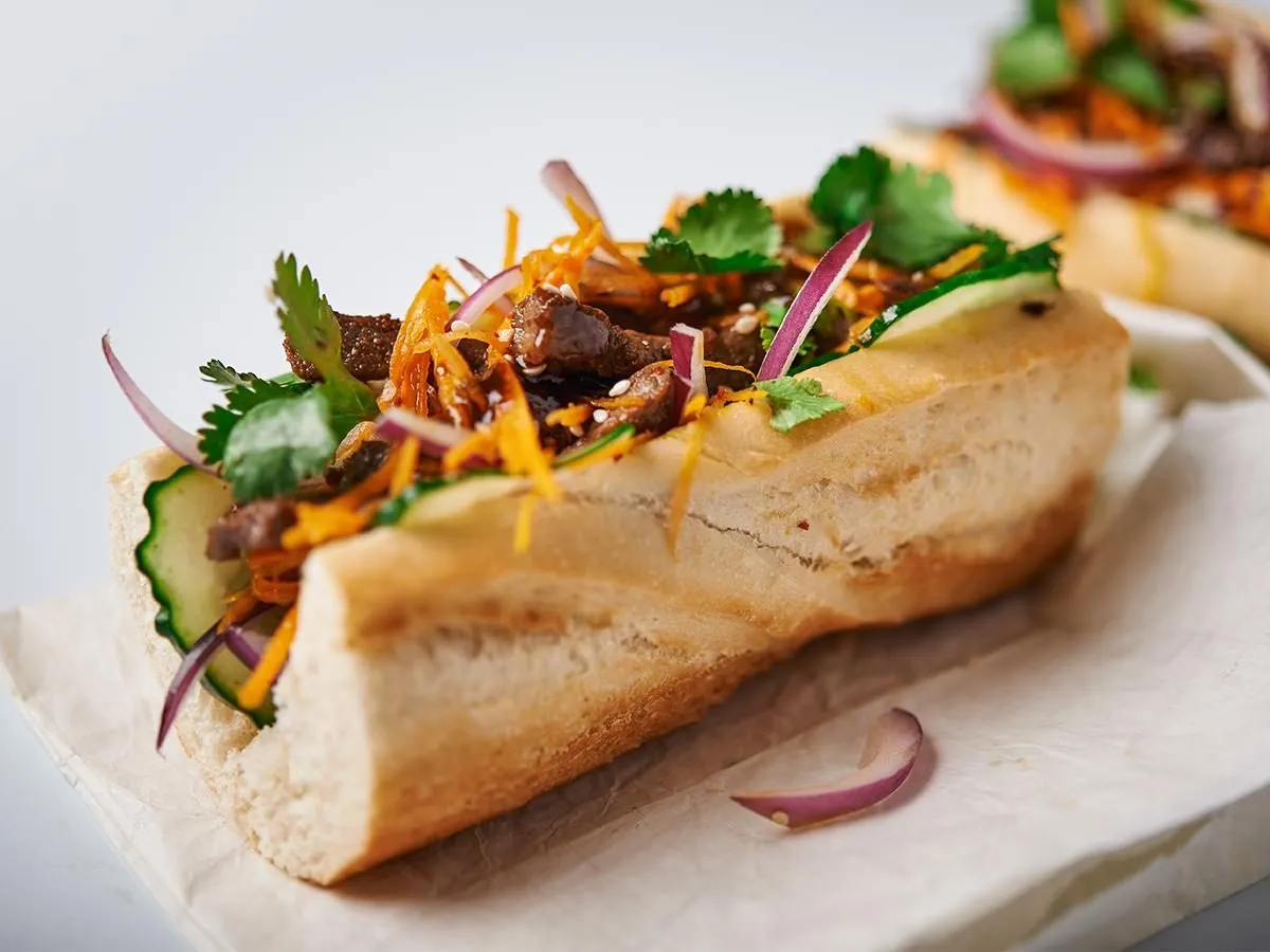 Pyszny banh mi przepis: chrupiąca bagietka z wołowiną, świeżym og&oacute;rkiem, marchewką, kolendrą i czerwoną cebulą.
