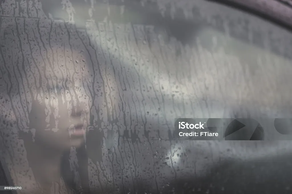 kobieta patrząca przez zaparowaną szybę w deszczu, symbol emocjonalnego chaosu