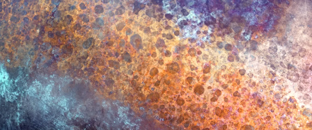 Tekstura przypominająca rdzę, z plamami w odcieniach pomarańczu, brązu i fioletu. Czy mosiądz rdzewieje? Ten obraz sugeruje, że tak.