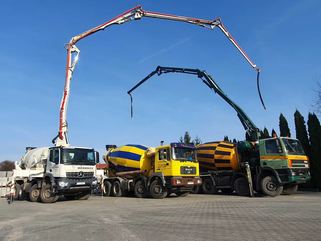 Trzy betonomieszarki z wysięgnikami, gotowe do pracy. Zastanawiasz się, ile kosztuje gruszka betonu?