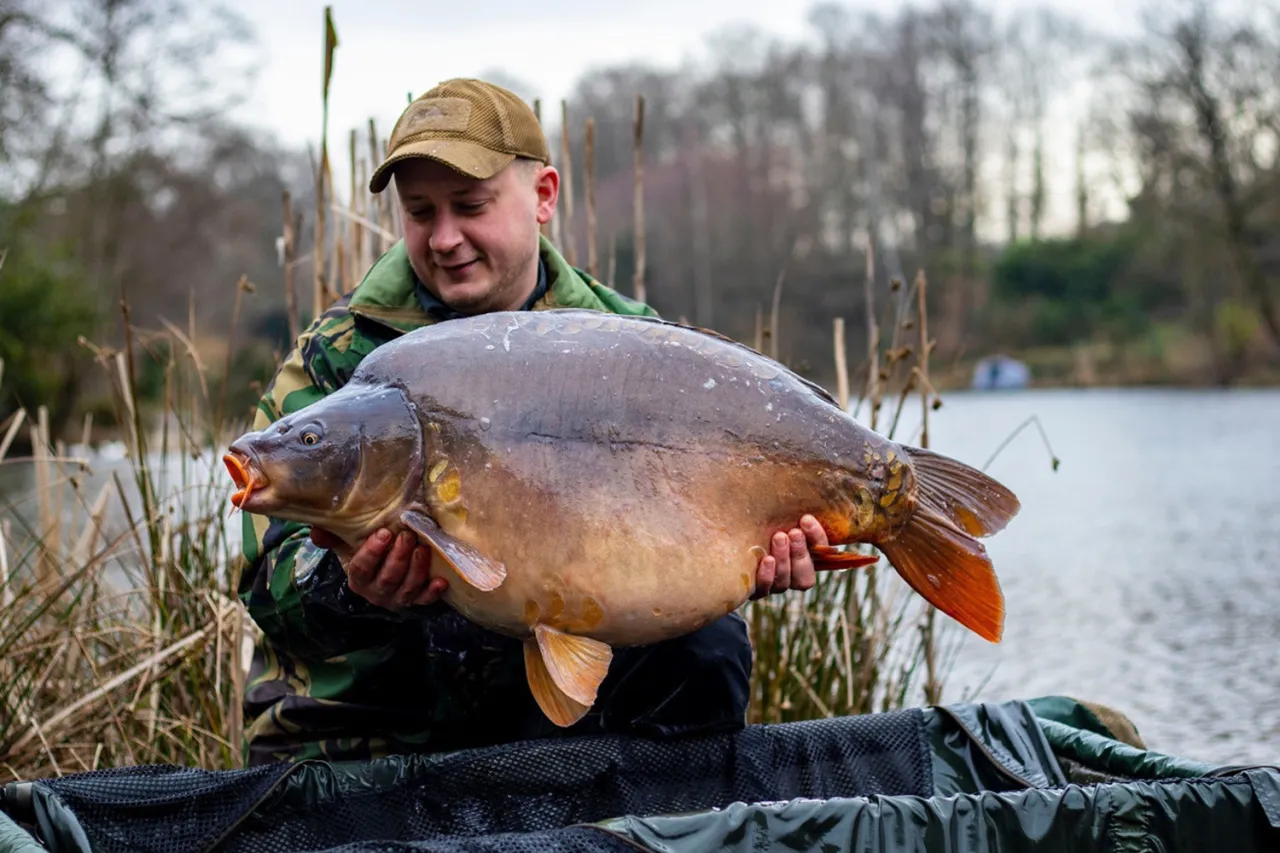 Wędkarz z dumą prezentuje okazałego karpia. Zastanawiasz się, jaka zanęta na karpia przyniosła taki sukces?