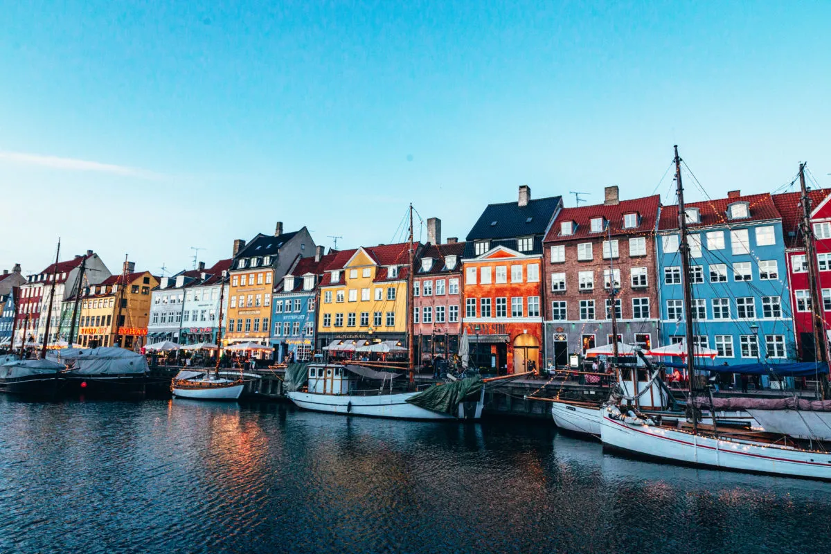 Kolorowe kamienice nad kanałem Nyhavn to idealne miejsce, by zacząć zwiedzać Kopenhagę. Łodzie cumują przy nabrzeżu.