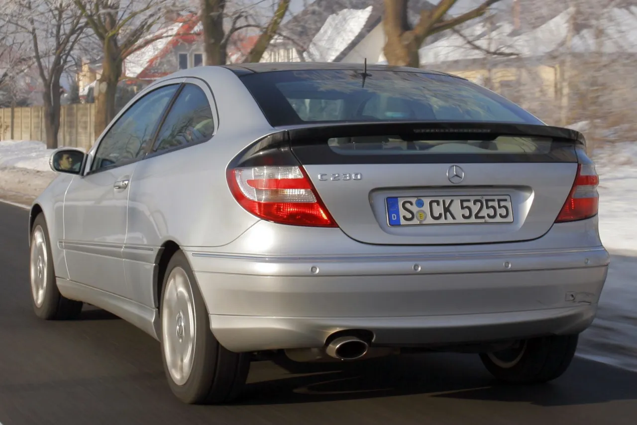 Srebrny Mercedes-Benz W203 1.8 Kompressor z czarnym spojlerem na klapie bagażnika, jadący po zimowej drodze.