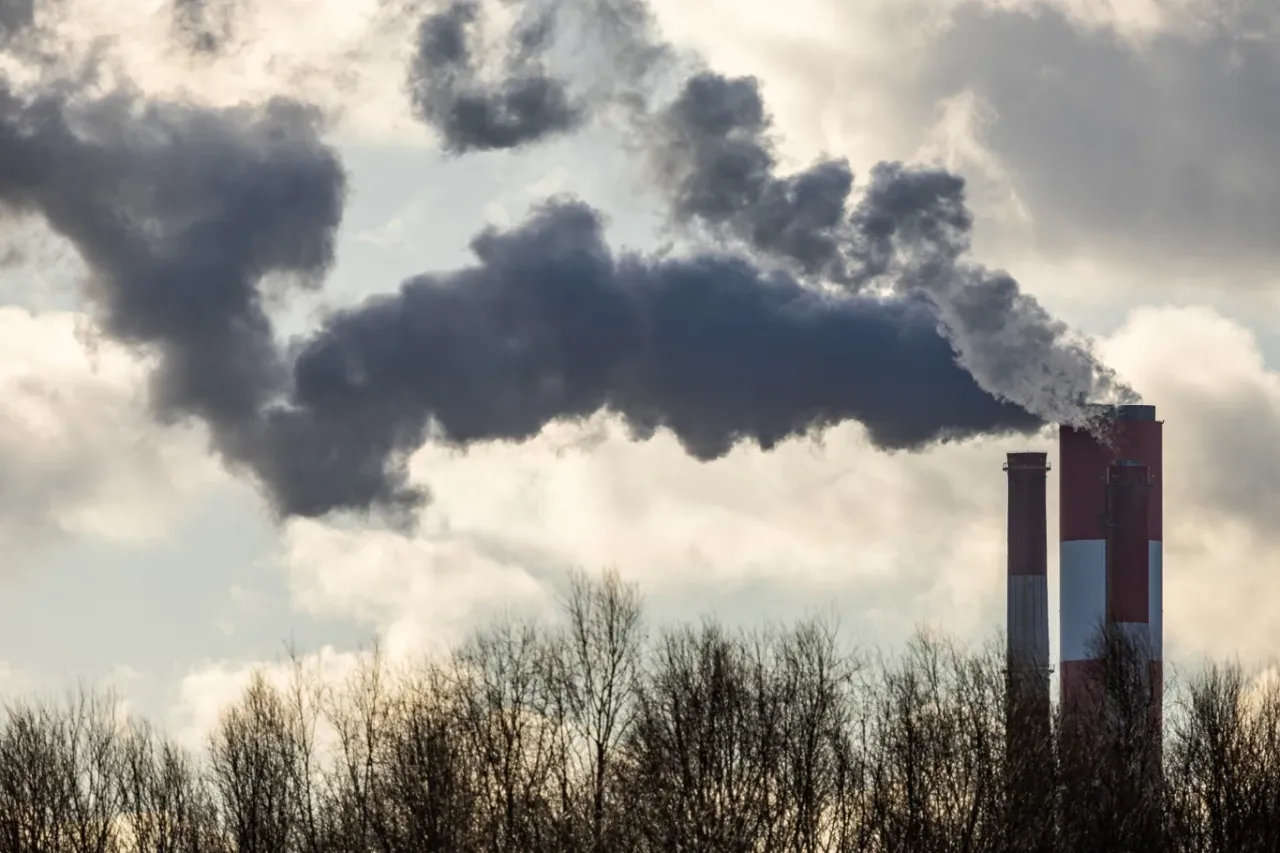 Dym z komin&oacute;w przemysłowych, w tym z zakładu eu ets, unosi się na tle pochmurnego nieba.