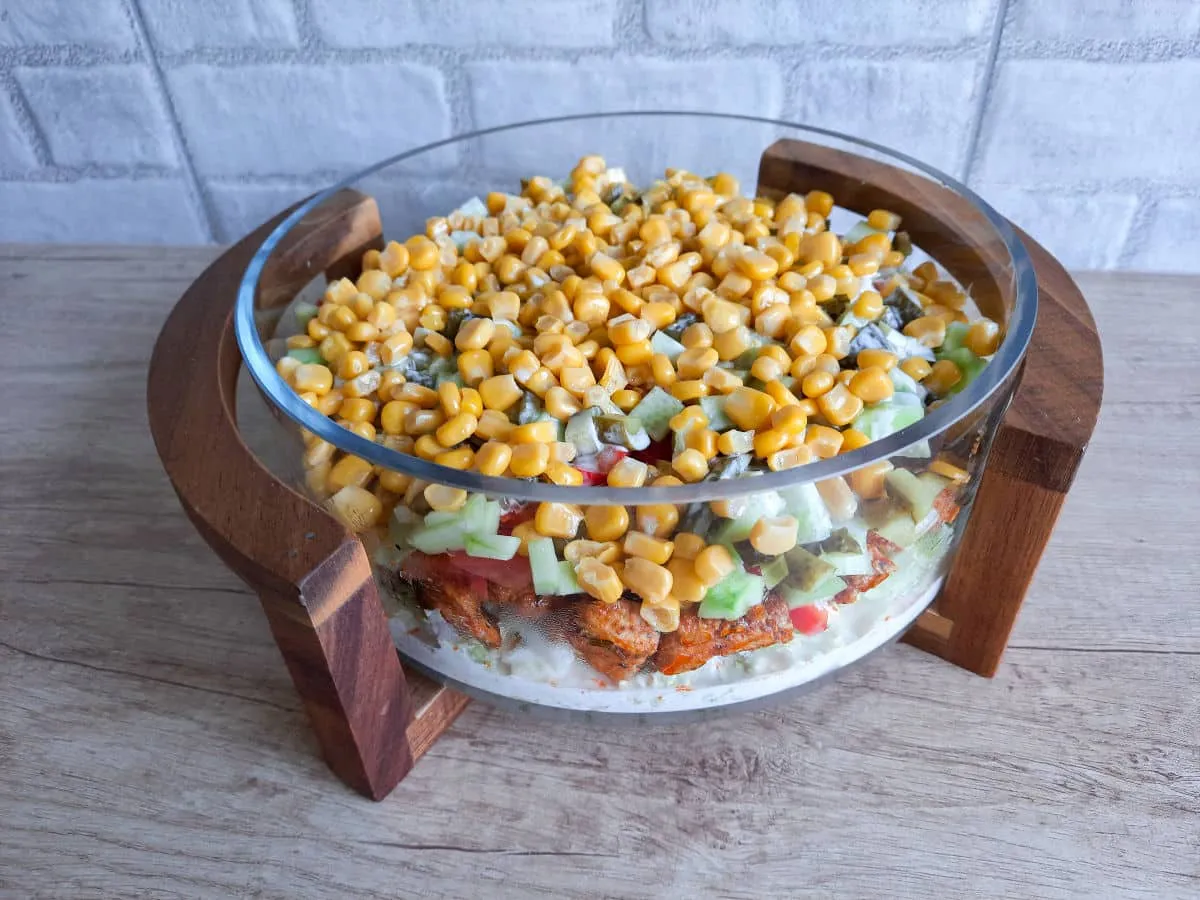 Warstwowa sałatka z kurczakiem, kukurydzą, ogórkiem i pomidorem, idealna jako dodatek do sałatki gyros.
