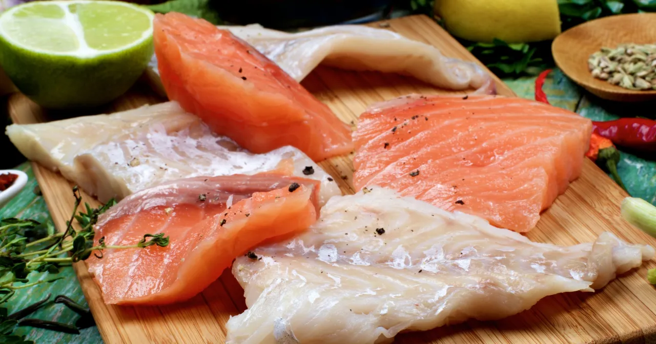 Stek z łososia kontra polędwica z dorsza na desce, z limonką, cytryną i przyprawami.