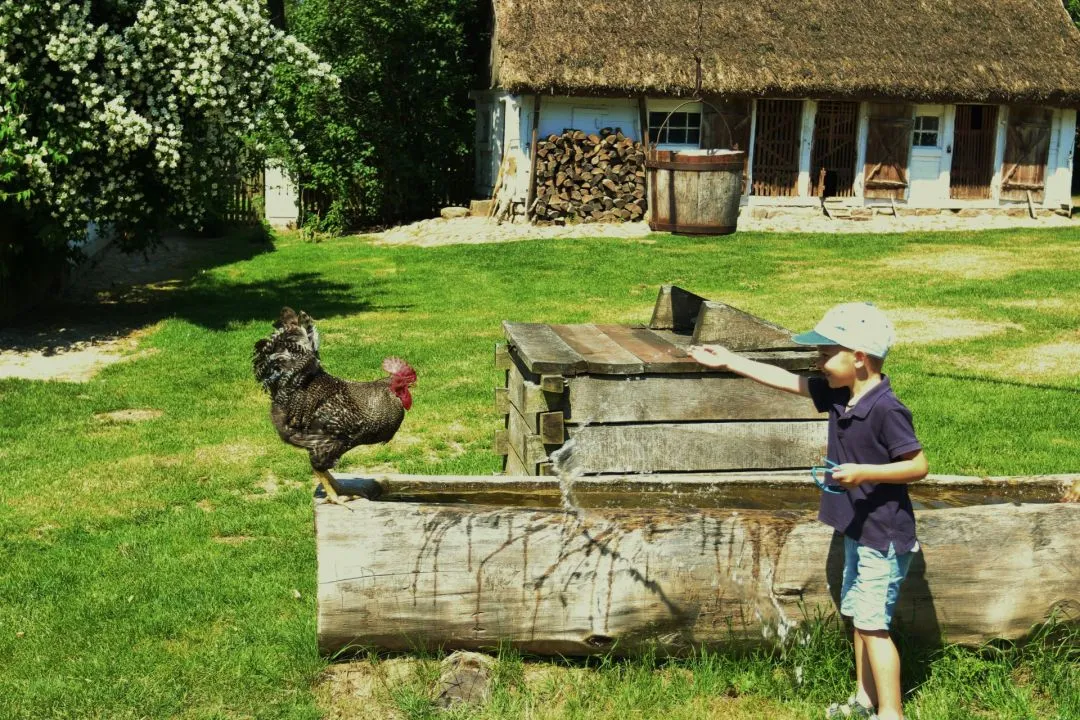 Rodzina zwiedzająca skansen, dzieci na warsztatach rzemieślniczych