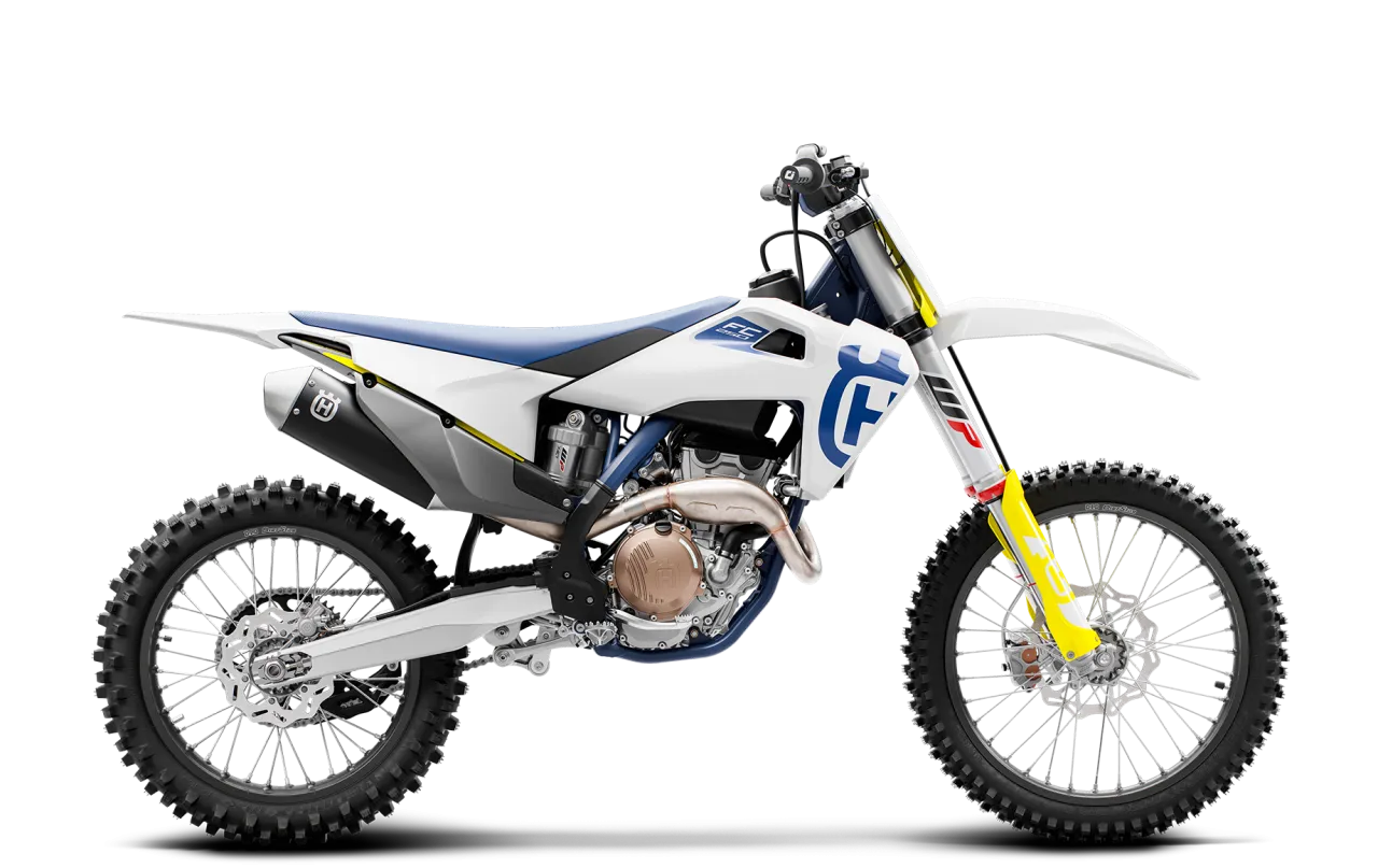 Biały motocykl Husqvarna FC 250 z niebieskim siedzeniem i ż&oacute;łtymi akcentami, gotowy do jazdy po torze.