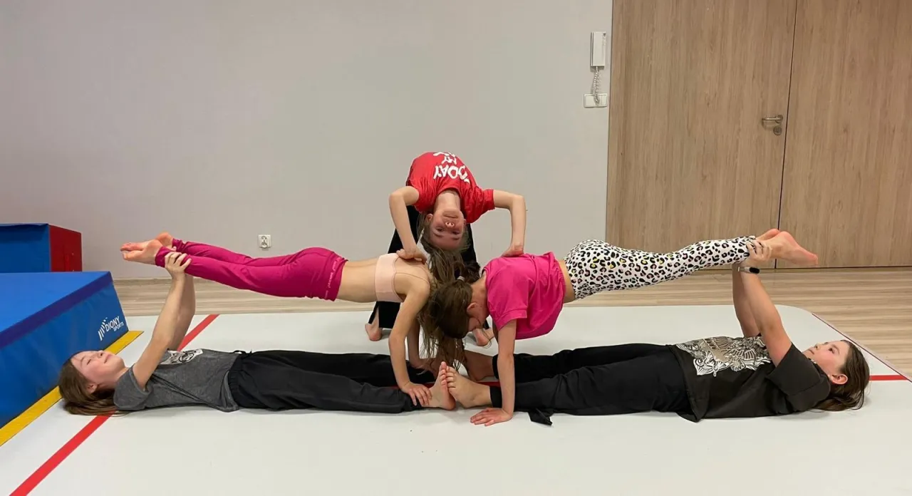 dzieci ćwiczące akrobatykę na macie