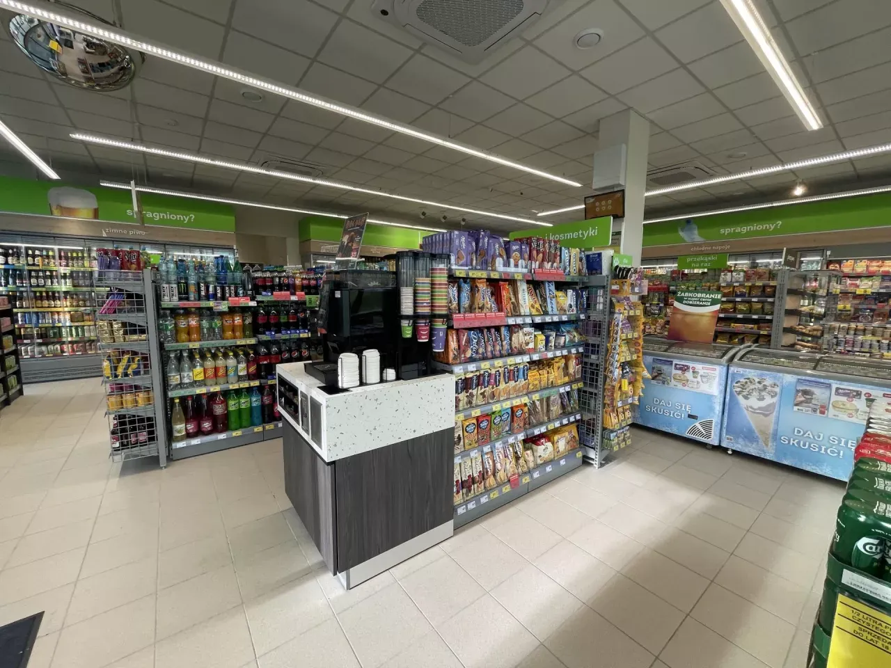 Wnętrze nowoczesnego sklepu Żabka z widocznymi produktami convenience