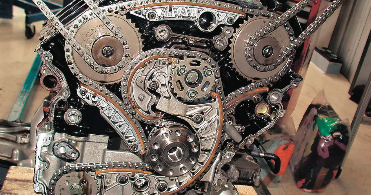 Złożony mechanizm rozrządu na łańcuchu z widocznymi kołami zębatymi i napinaczami.