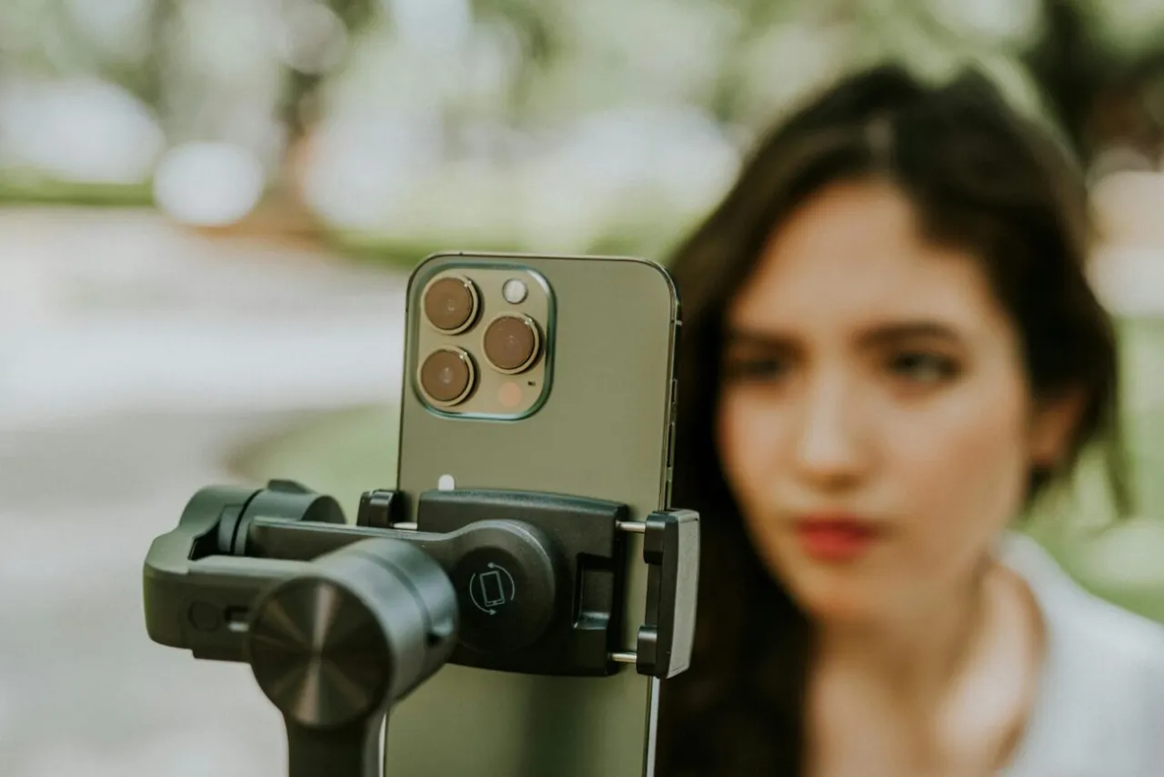Młoda content creator nagrywa siebie na telefonie zamontowanym na gimbalu.