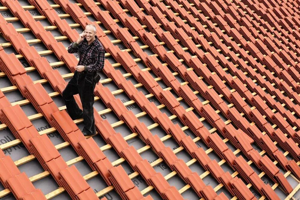 dekarz przy pracy na dachu domu jednorodzinnego
