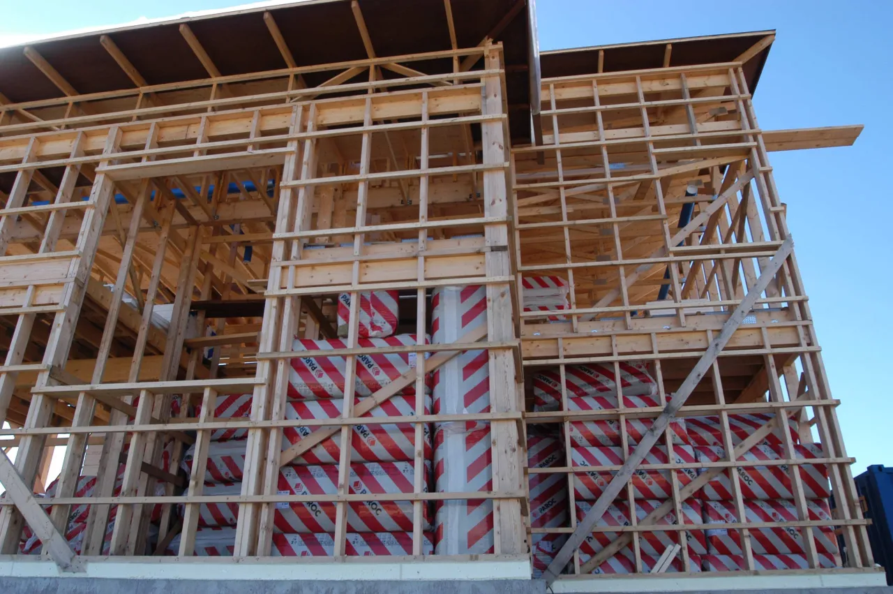 Szkielet domu w budowie, widoczne belki drewniane i pakiety izolacji. Trudno ocenić, ile wytrzyma dom szkieletowy bez dalszych prac.