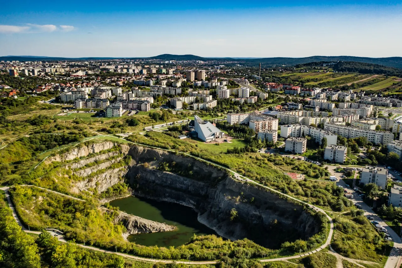 Widok na rezerwat przyrody Ślichowice z kamieniołomem i zbiornikiem wodnym, otoczony osiedlem mieszkaniowym i zielenią.