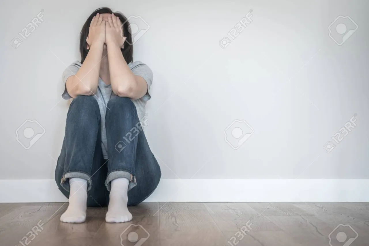 osoba siedząca samotnie w pustym pokoju