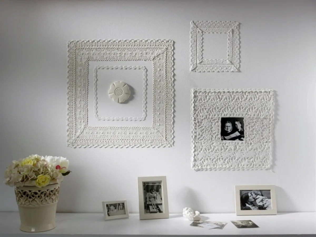Dekoracje ścienne z gipsu: ażurowe ramki na zdjęcia i ozdobny medalion tworzą elegancką kompozycję.