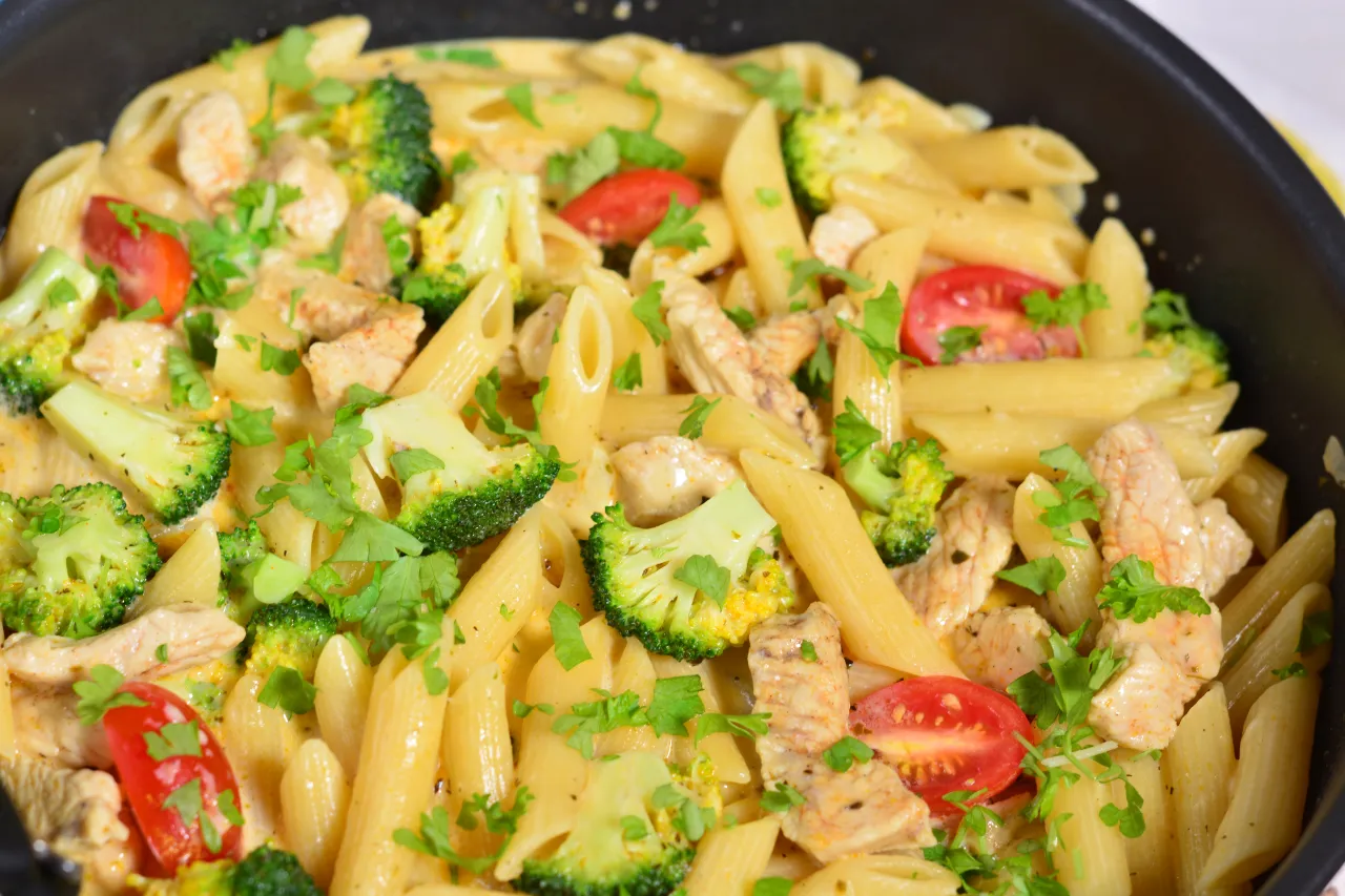 Penne z kurczakiem i brokułami w kremowym sosie, posypane natką pietruszki. Idealny przepis na szybki obiad.