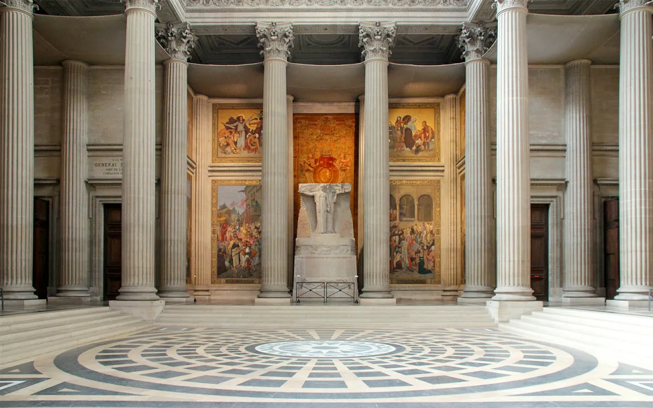 Wnętrze Panteonu w Paryżu z monumentalnymi kolumnami, mozaikami i rzeźbą na piedestale.