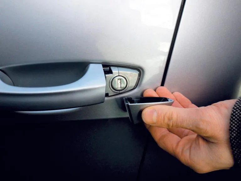 Samochód z otwartymi drzwiami, kierowca sprawdza zamek
