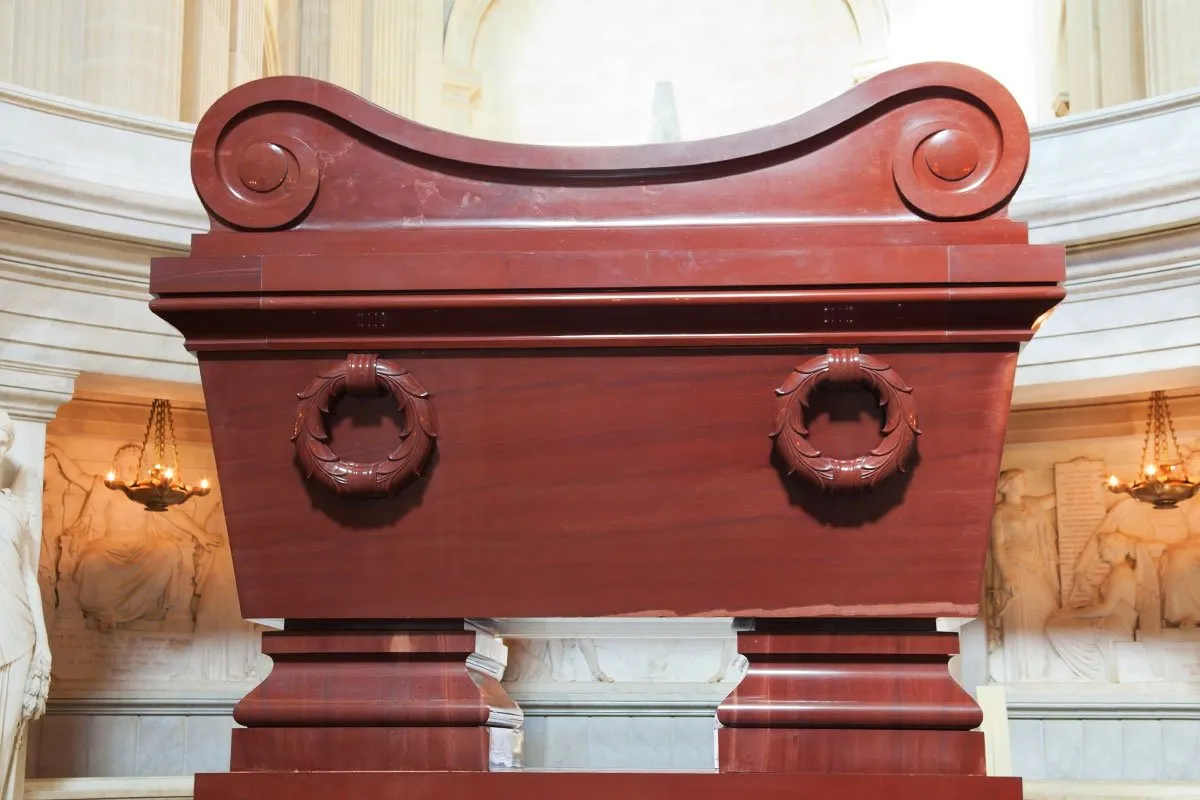 Imponujący sarkofag z czerwonego porfiru, gdzie jest pochowany Napoleon, ozdobiony wieńcami laurowymi.