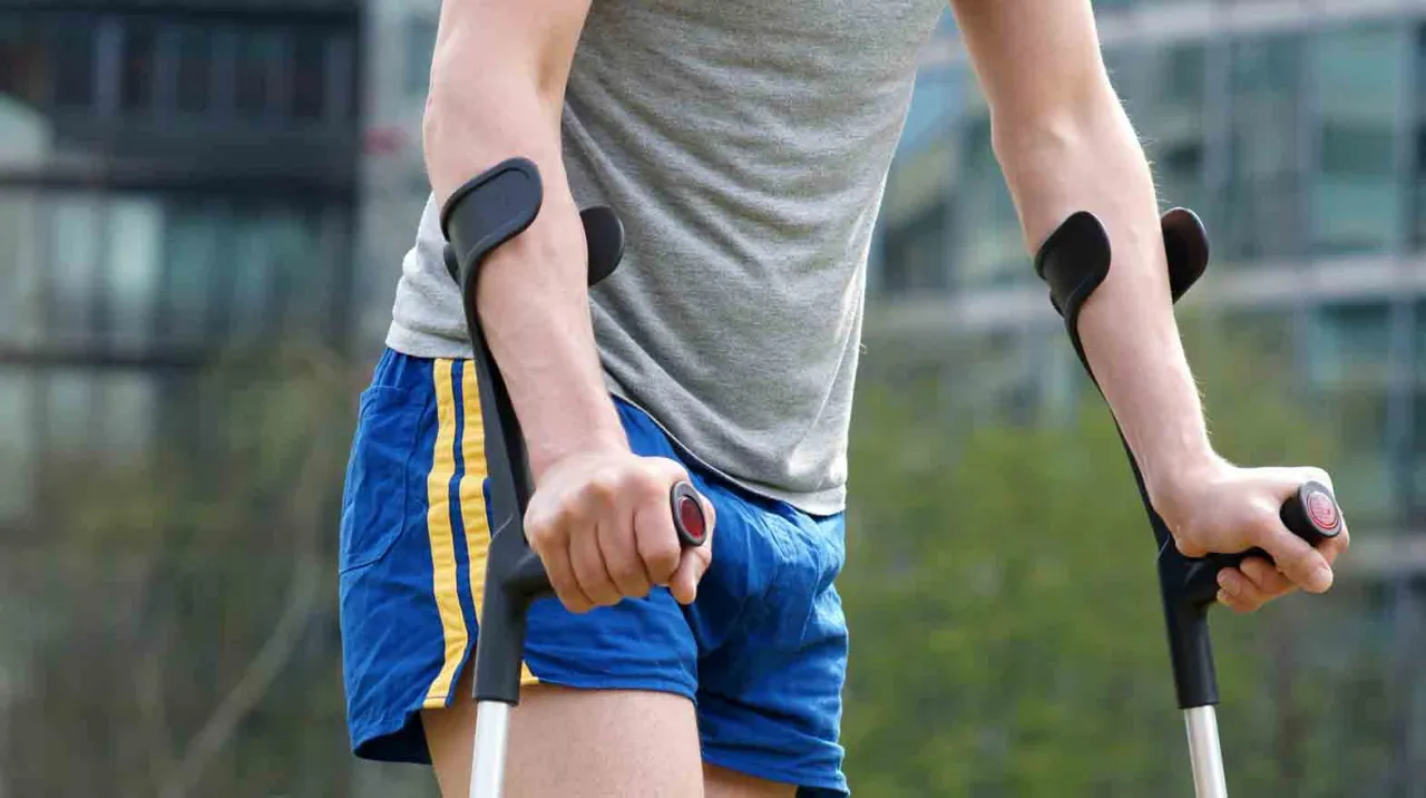 Mężczyzna na kulach, zastanawiający się, czy skręcenie stawu skokowego jest trwałym uszczerbkiem na zdrowiu.