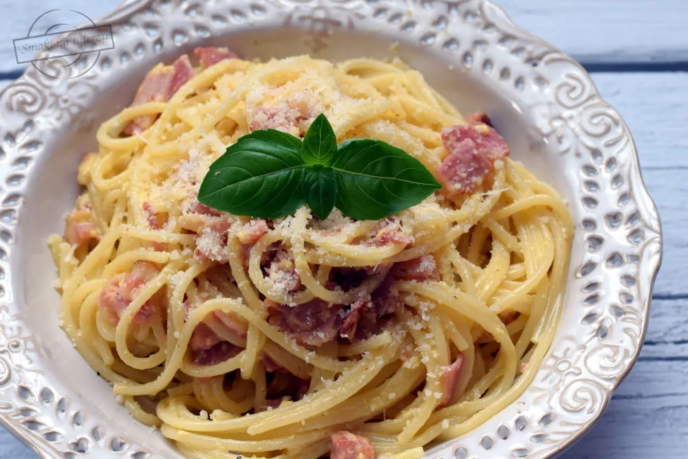 apetyczne spaghetti carbonara na talerzu z widocznym boczkiem i serem
