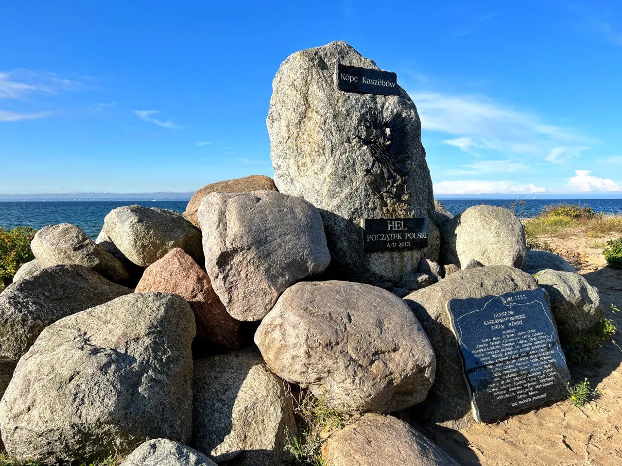 Kamienny Kopiec Kaszubów na plaży na cyplu helskim, z widokiem na morze i błękitne niebo.