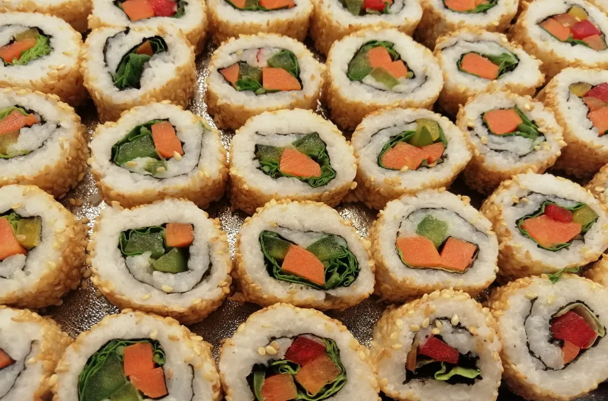 Roladki sushi z sezamem, w środku zielona sałata, marchewka i og&oacute;rek. Idealne warzywa do sushi na lekki posiłek.