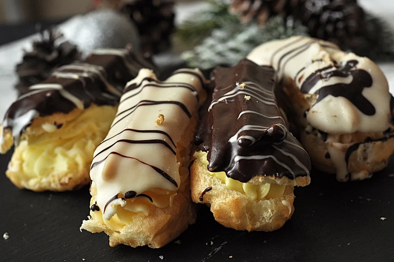 Pyszne eklerki przepis na święta. Kremowe wnętrze, czekoladowa i biała polewa, ozdobione lukrem. Idealne na deser.