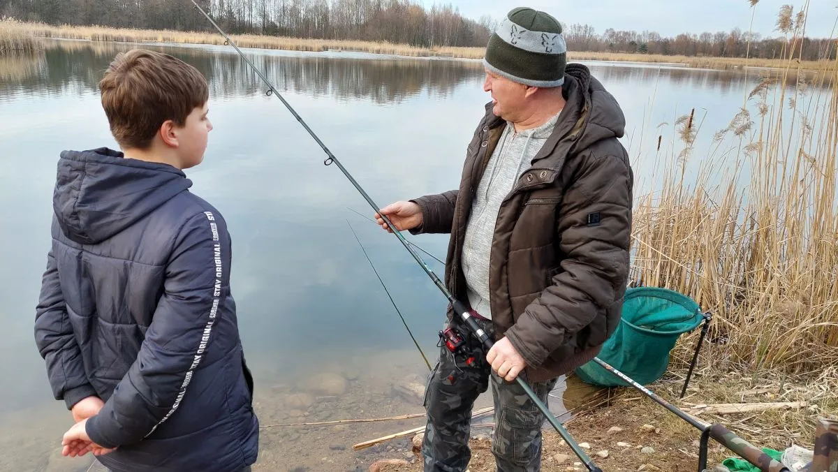 młody wędkarz z wędką i opiekunem