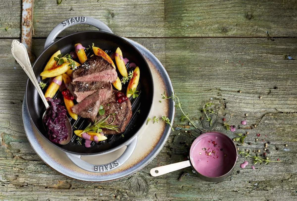 Soczysty stek z ziemniakami i czerwoną kapustą, podany z aromatycznymi sosami do steka.