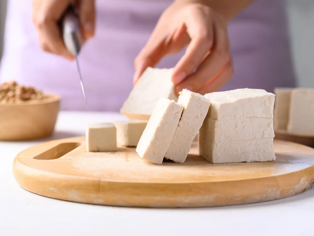 Krojenie tofu na desce. Czy tofu jest zdrowe? Tak, to wszechstronny składnik bogaty w białko.