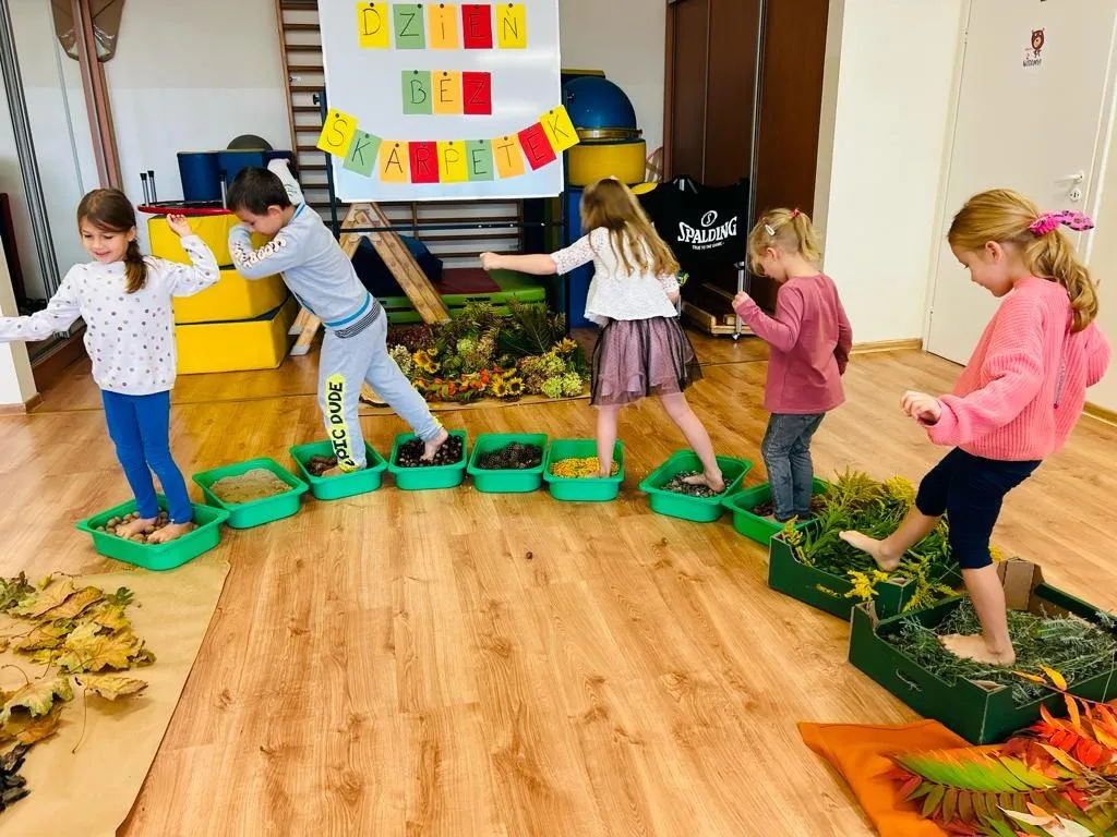 dzieci przechodzące po jesiennej ścieżce sensorycznej w przedszkolu