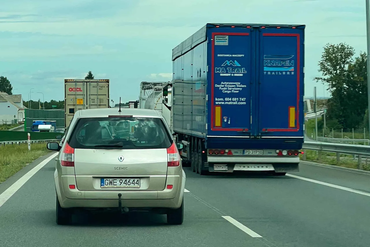 Samoch&oacute;d osobowy jedzie za tirem na autostradzie. Kierowca zastanawia się, czy wyprzedzanie tirem w tym miejscu nie skończy się mandatem.