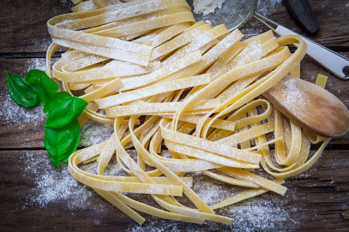 Świeży makaron bezglutenowy, posypany mąką, z listkami bazylii. Idealny przepis na domowy makaron bez glutenu.