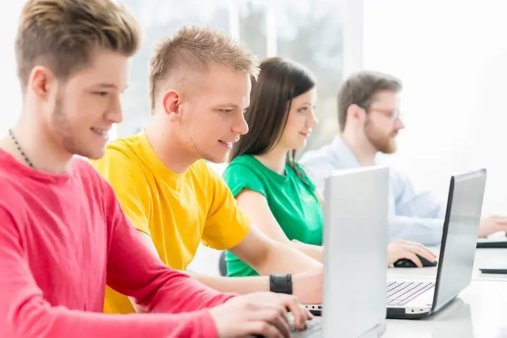 dzieci uczące się programowania na tabletach lub laptopach