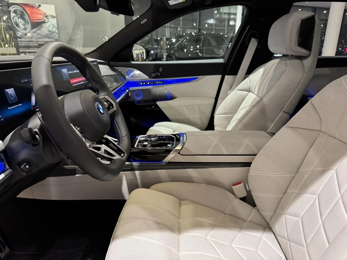 Wnętrze nowego BMW Serii 7 z białymi, pikowanymi fotelami i niebieskim ambientowym oświetleniem. Zastanawiasz się, ile kosztuje nowe BMW 7?