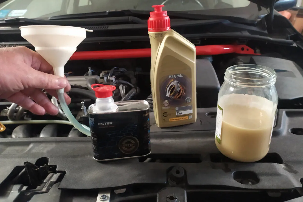 Przygotowanie do wymiany oleju w Toyota Corolla 1.6 benzyna. Widać lejek, butelkę oleju Manual 75W i słoik z płynem.