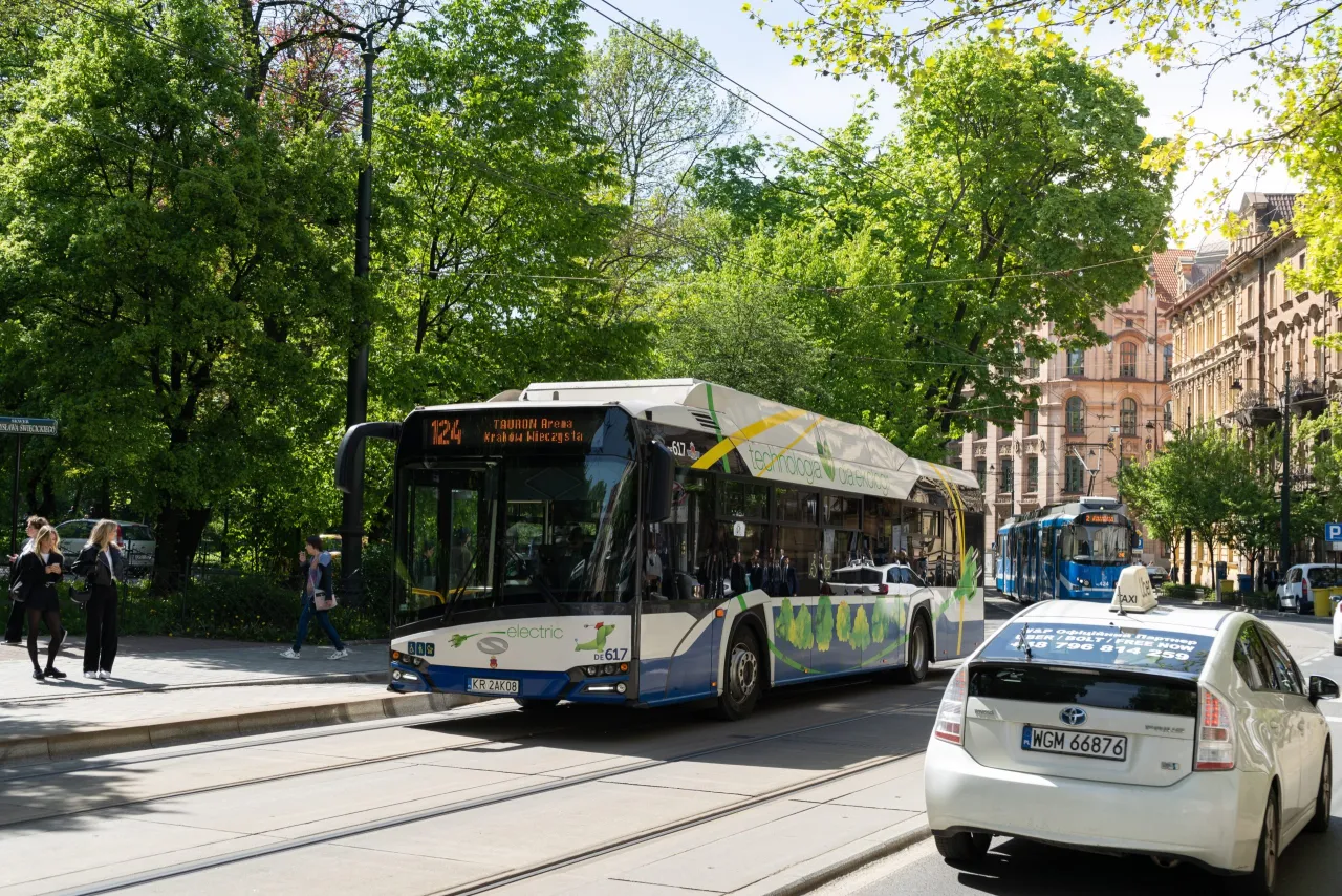 Elektryczny autobus i hybrydowa taks&oacute;wka na ulicy to kroki, jak zmniejszyć zanieczyszczenie środowiska.