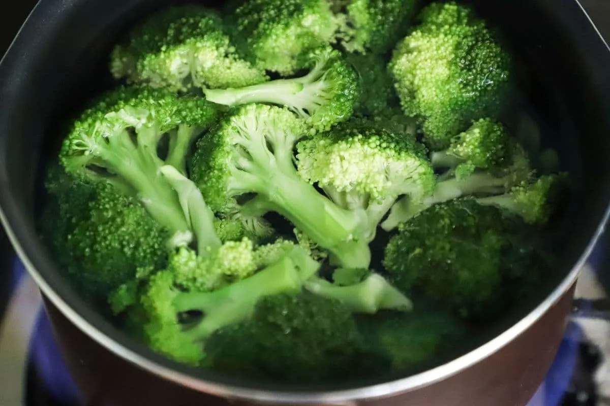Zielone r&oacute;życzki brokuł&oacute;w gotują się w garnku, przygotowywane do pysznej sałatki.