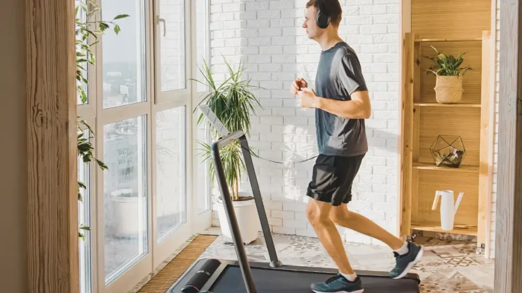 Osoba biegnąca na bieżni przed treningiem siłowym